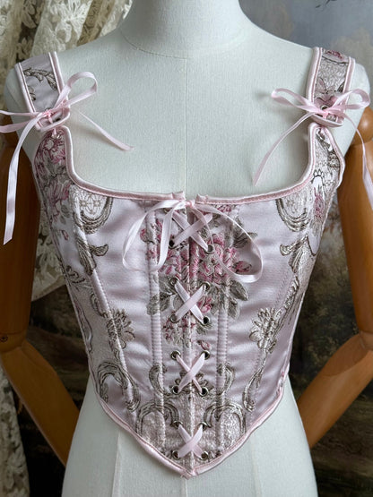 Historical fashion inspired baroque to rococo era front-laced corset stays top in pastel pink floral jacquard fabric, pictured on a mannequin.