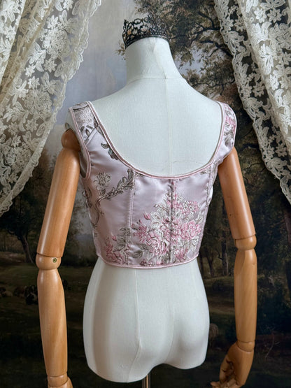 Historical fashion inspired baroque to rococo era front-laced corset stays top in pastel pink floral jacquard fabric, pictured on a mannequin.