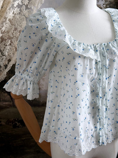 A vintage style historically-inspired white and blue floral print cotton button-up blouse with scalloped lace collar and trim, pictured on a mannequin.