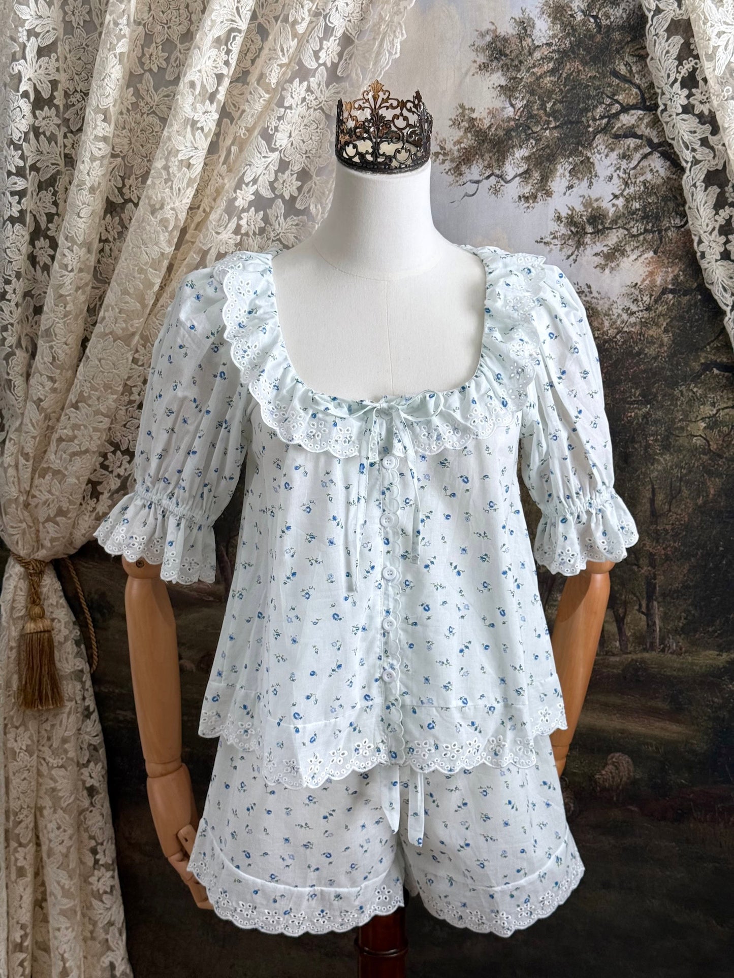 A vintage style historically-inspired set of white and blue floral print cotton button-up blouse and bloomer shorts with scalloped lace collar and trim, pictured on a mannequin.