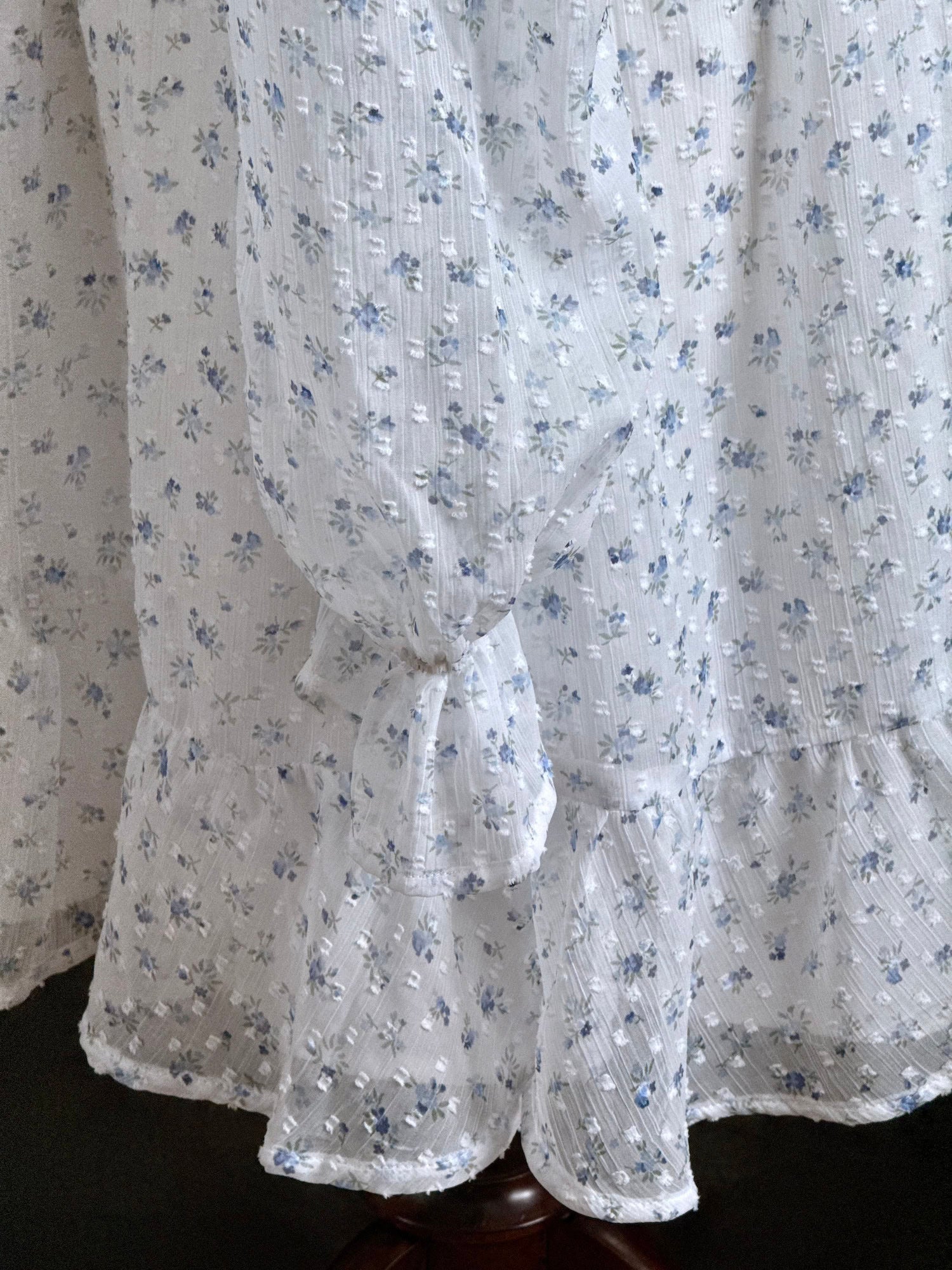 Sleeve detail on a historically Inspired regency style empire waist mini dress with ruffle hem, ruched bodice, and tulip sleeves made of white and blue floral chiffon. 