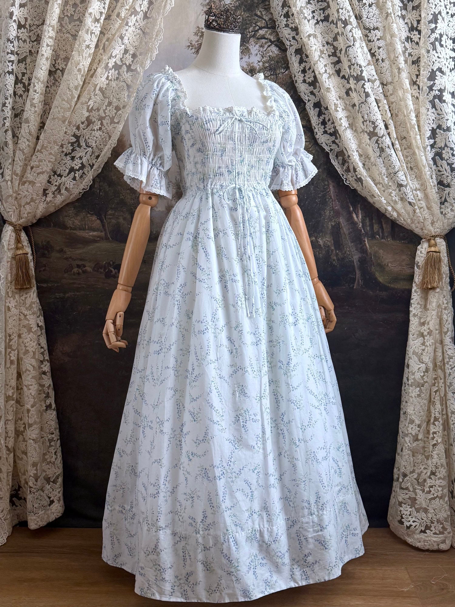 A Historically Inspired regency style puff sleeve White Floral Print Cotton Chemise maxi Dress with Shirred bodice, drawstring cinching laces, and lace trim.