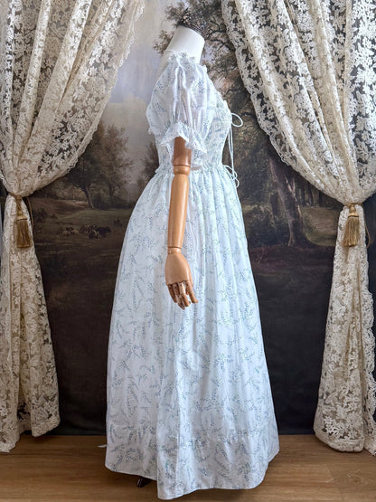 A Historically Inspired regency style puff sleeve White Floral Print Cotton Chemise maxi Dress with Shirred bodice, drawstring cinching laces, and lace trim.
