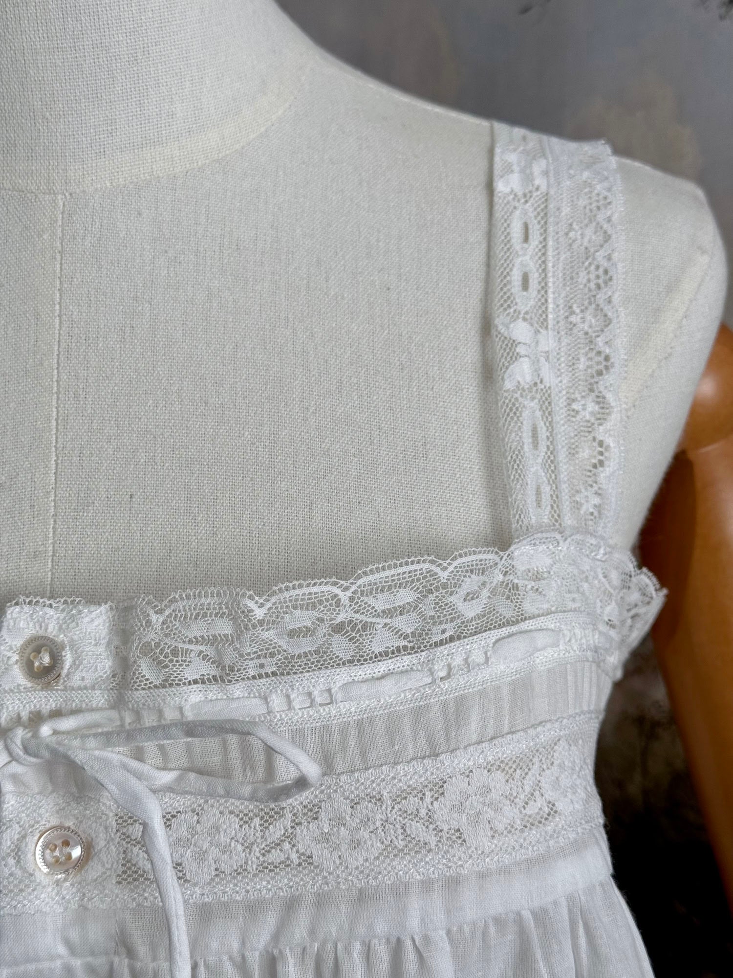 close up of a victorian / edwardian inspired antique corset cover style tank top blouse made from white cotton and vintage design lace, pictured on a mannequin.