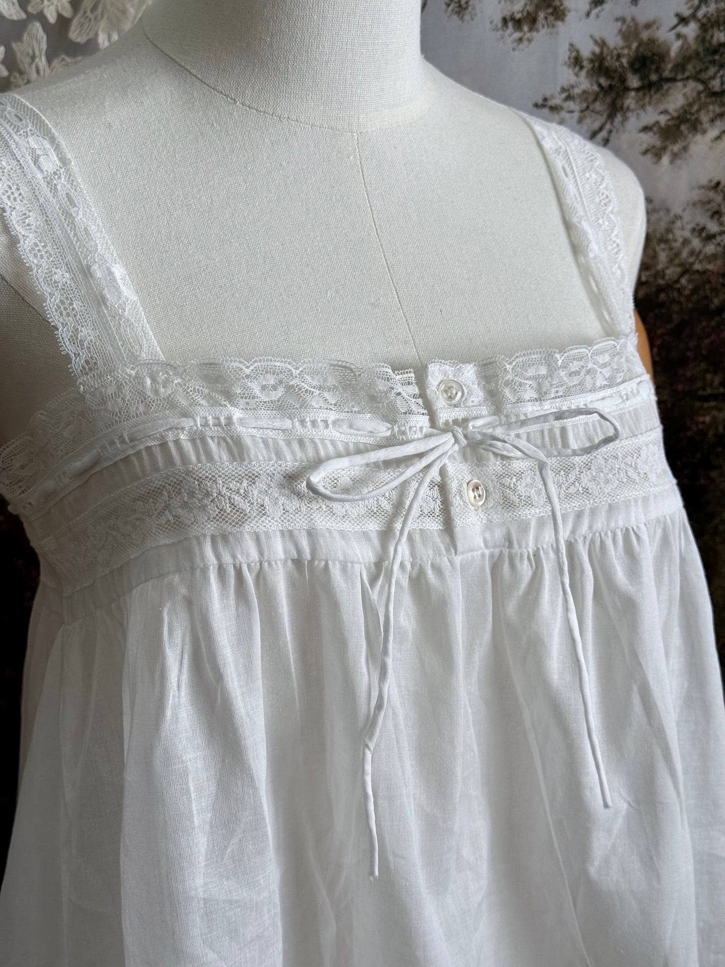 Close up of A victorian / edwardian inspired antique corset cover style tank top blouse made from white cotton and vintage design lace, pictured on a mannequin.