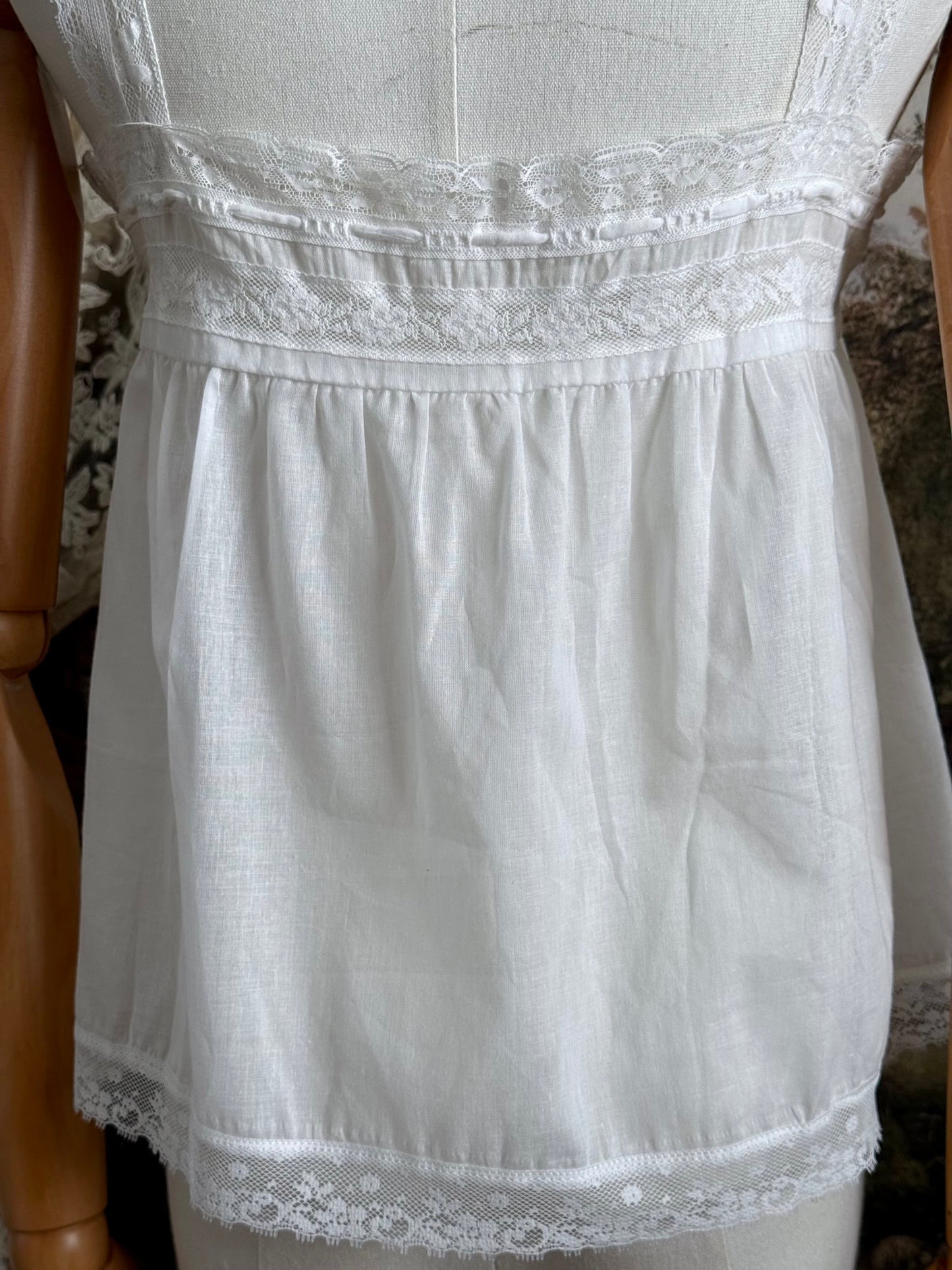 A victorian / edwardian inspired antique corset cover style tank top blouse made from white cotton and vintage design lace, pictured on a mannequin.