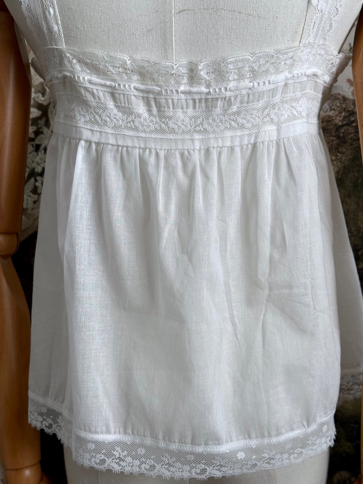 A victorian / edwardian inspired antique corset cover style tank top blouse made from white cotton and vintage design lace, pictured on a mannequin.