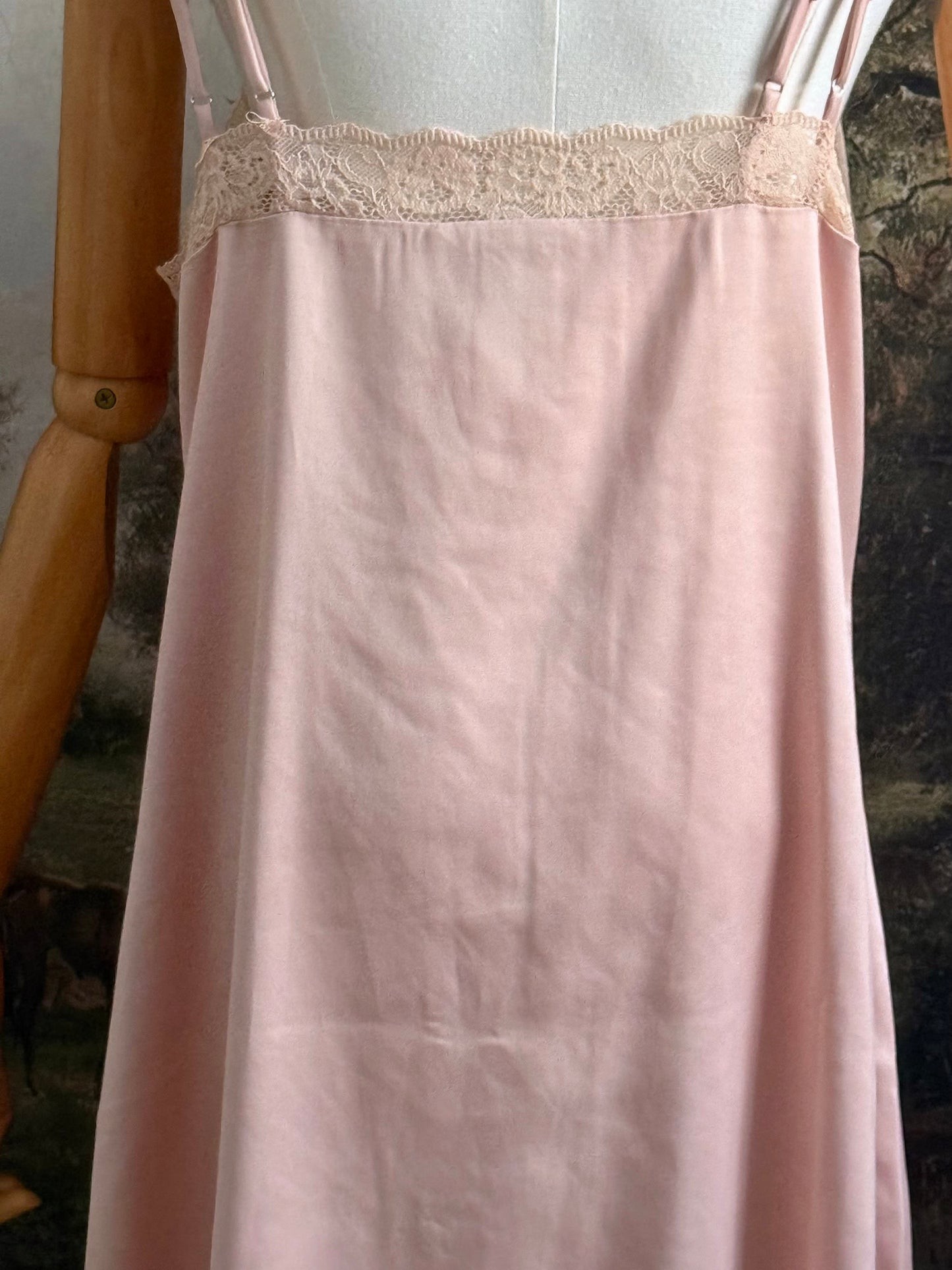 A historically inspired vintage style peachy pink satin overdress with covered buttons and lace trim on a mannequin