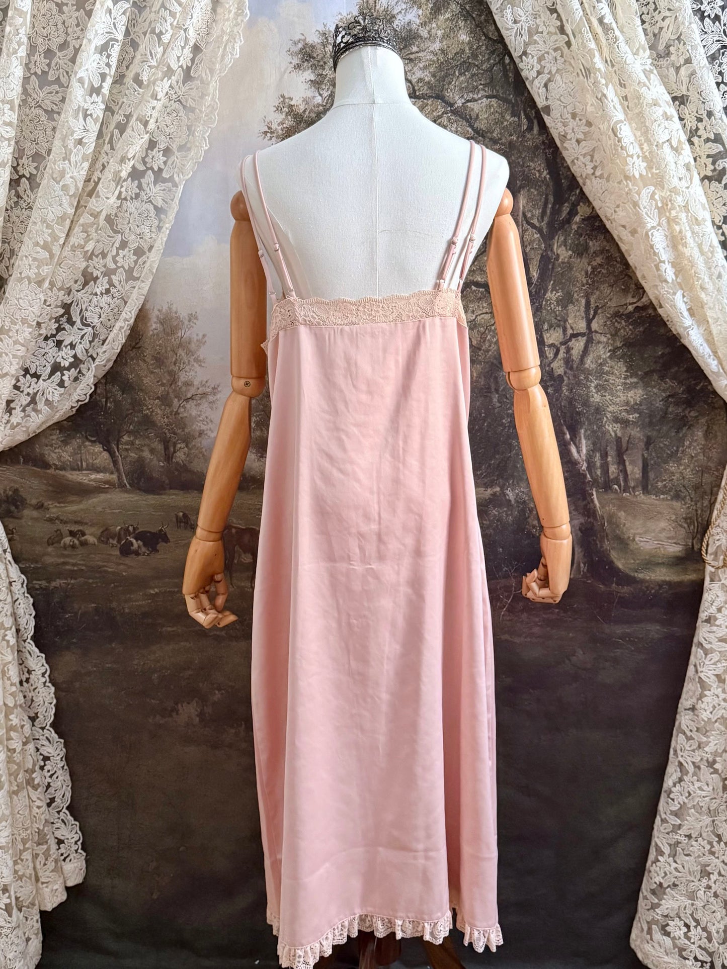 A historically inspired vintage style peachy pink satin overdress with covered buttons and lace trim on a mannequin