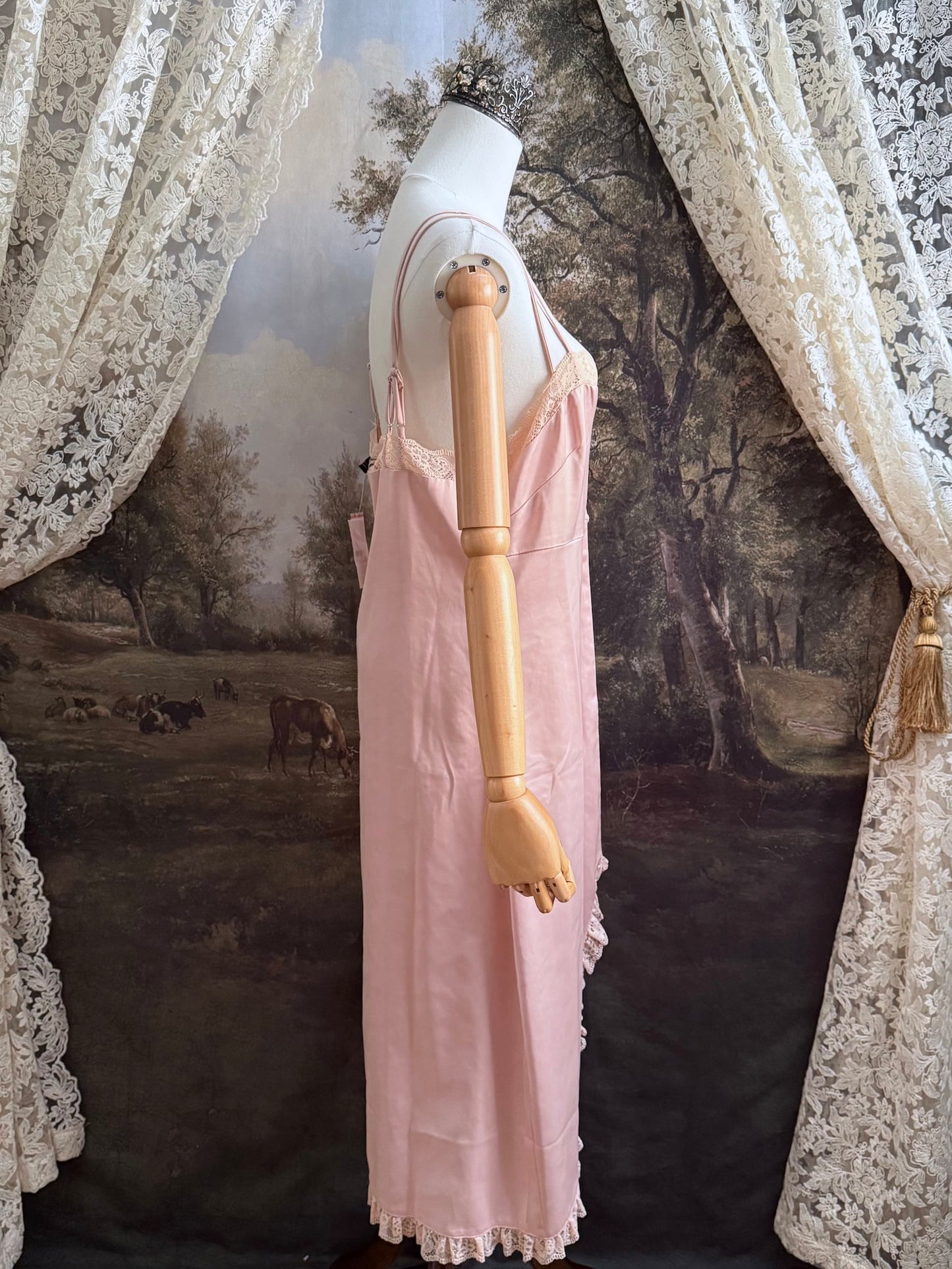 A historically inspired vintage style peachy pink satin overdress with covered buttons and lace trim on a mannequin