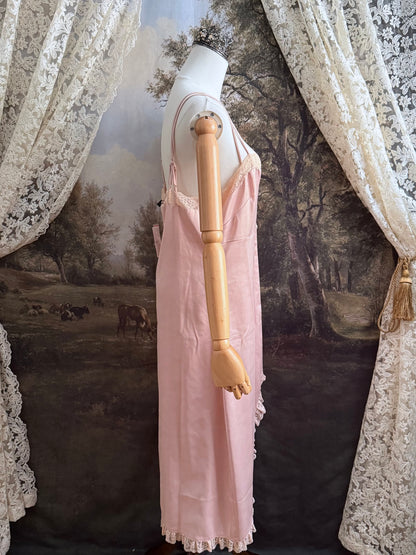 A historically inspired vintage style peachy pink satin overdress with covered buttons and lace trim on a mannequin