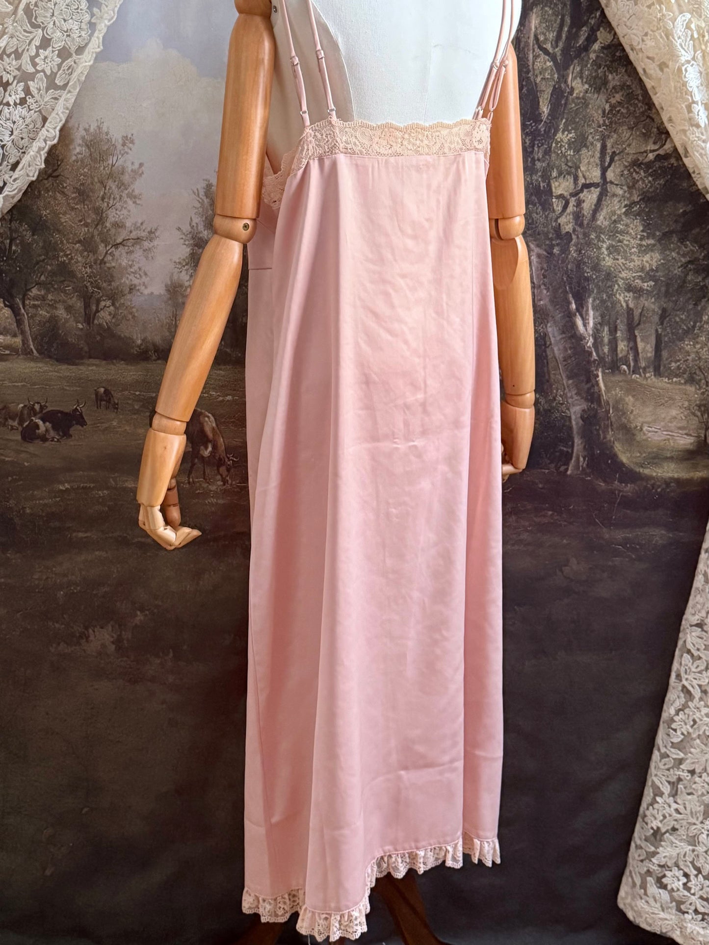 A historically inspired vintage style peachy pink satin overdress with covered buttons and lace trim on a mannequin