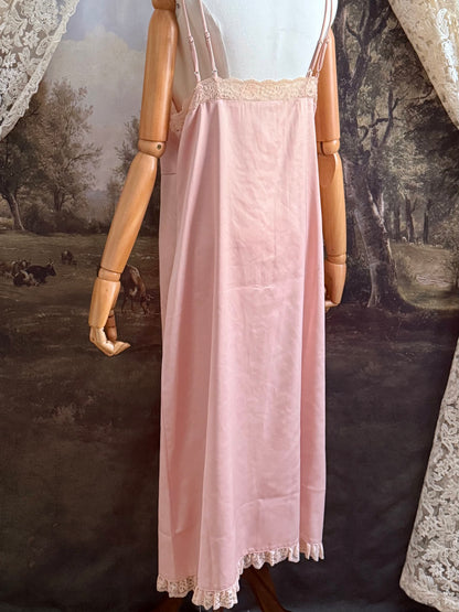 A historically inspired vintage style peachy pink satin overdress with covered buttons and lace trim on a mannequin