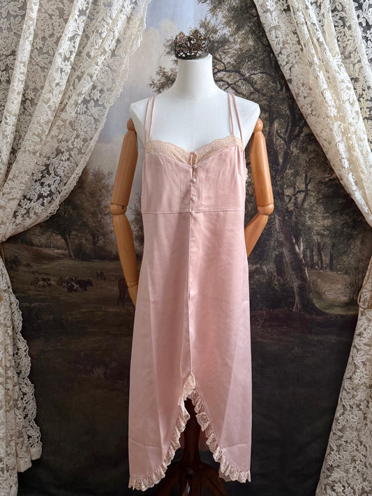 A historically inspired vintage style peachy pink satin overdress with covered buttons and lace trim on a mannequin