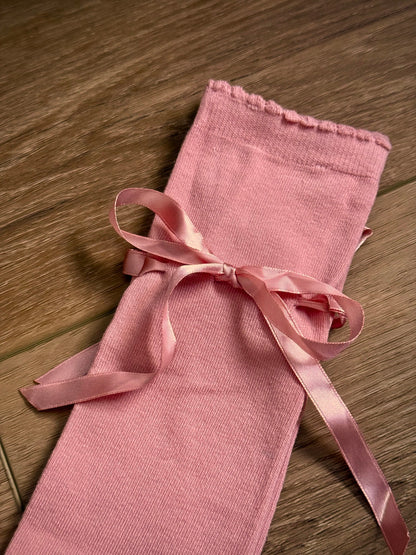 Details of historically inspired knee high stocking socks in a peach ballerina pink, laying on a wooden cottage floor. For edwardian, victorian, regency, rococo, baroque, renaissance, and medieval era fashion.