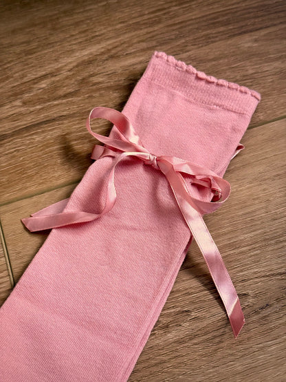 Details of historically inspired knee high stocking socks in a peach ballerina pink, laying on a wooden cottage floor. For edwardian, victorian, regency, rococo, baroque, renaissance, and medieval era fashion.