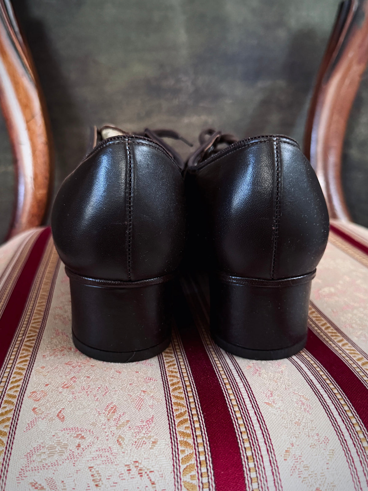 Dark brown leather vintage 1970s oxford derby shoes with heels and a textured pattern. Reminiscent of the 1940's. Pictured on a red and cream striped chair.