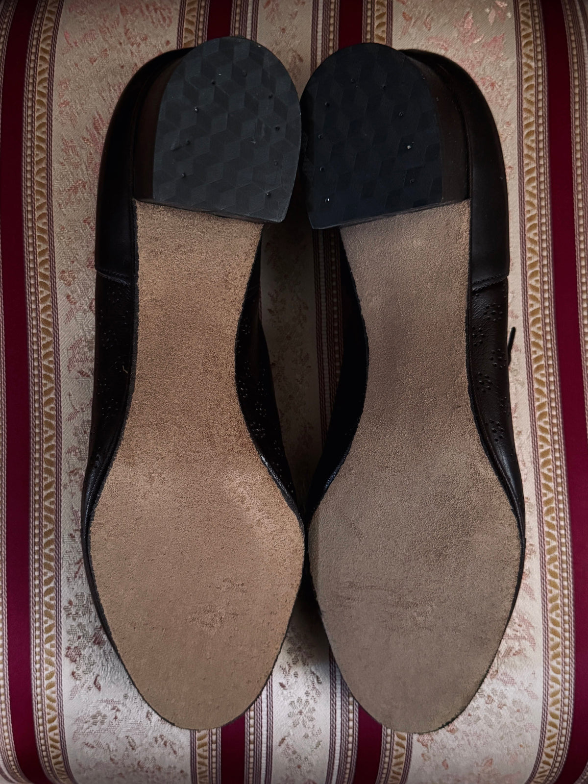 Dark brown leather vintage 1970s oxford derby shoes with heels and a textured pattern. Reminiscent of the 1940's. Pictured on a red and cream striped chair. Bottom view.