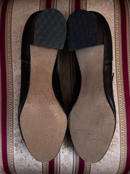 Dark brown leather vintage 1970s oxford derby shoes with heels and a textured pattern. Reminiscent of the 1940's. Pictured on a red and cream striped chair. Bottom view.