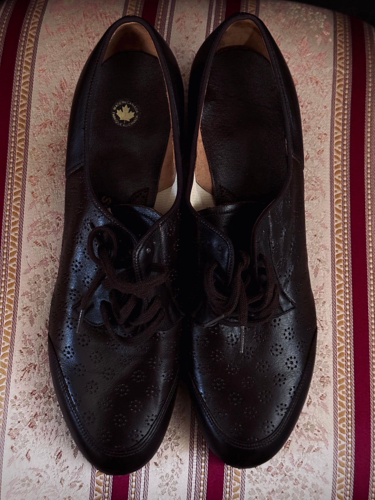 Dark brown leather vintage 1970s oxford derby shoes with heels and a textured pattern. Reminiscent of the 1940's. Pictured on a red and cream striped chair.